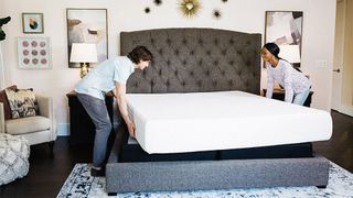 Best mattress on Amazon: Two people lifting the Signature Design by Ashley Chime mattress onto a bed