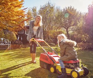 Mum and daughter mowing grass in autumn