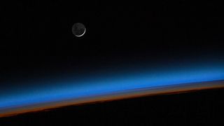 Photo captured by ESA astronaut Samantha Cristoforetti from onboard the International Space Station showing the Moon rising above the colors of the imminent sunrise.