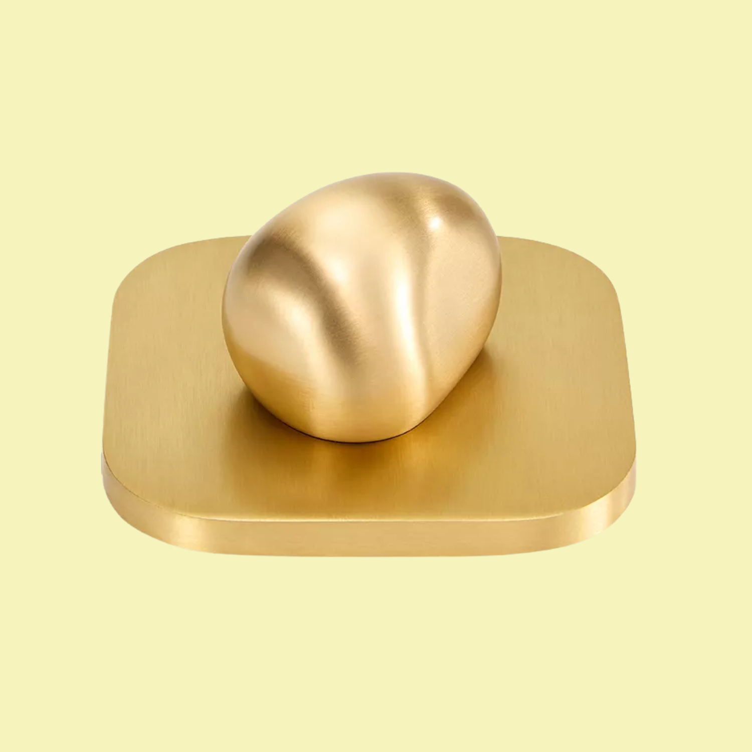 A brushed gold candle lid with a large pebble holder