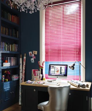 Luxury pink blinds in dark blue home office with wooden desk and silver upholstered chair