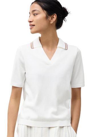 Woman wearing a Uniqlo white polo shirt in front of a white background