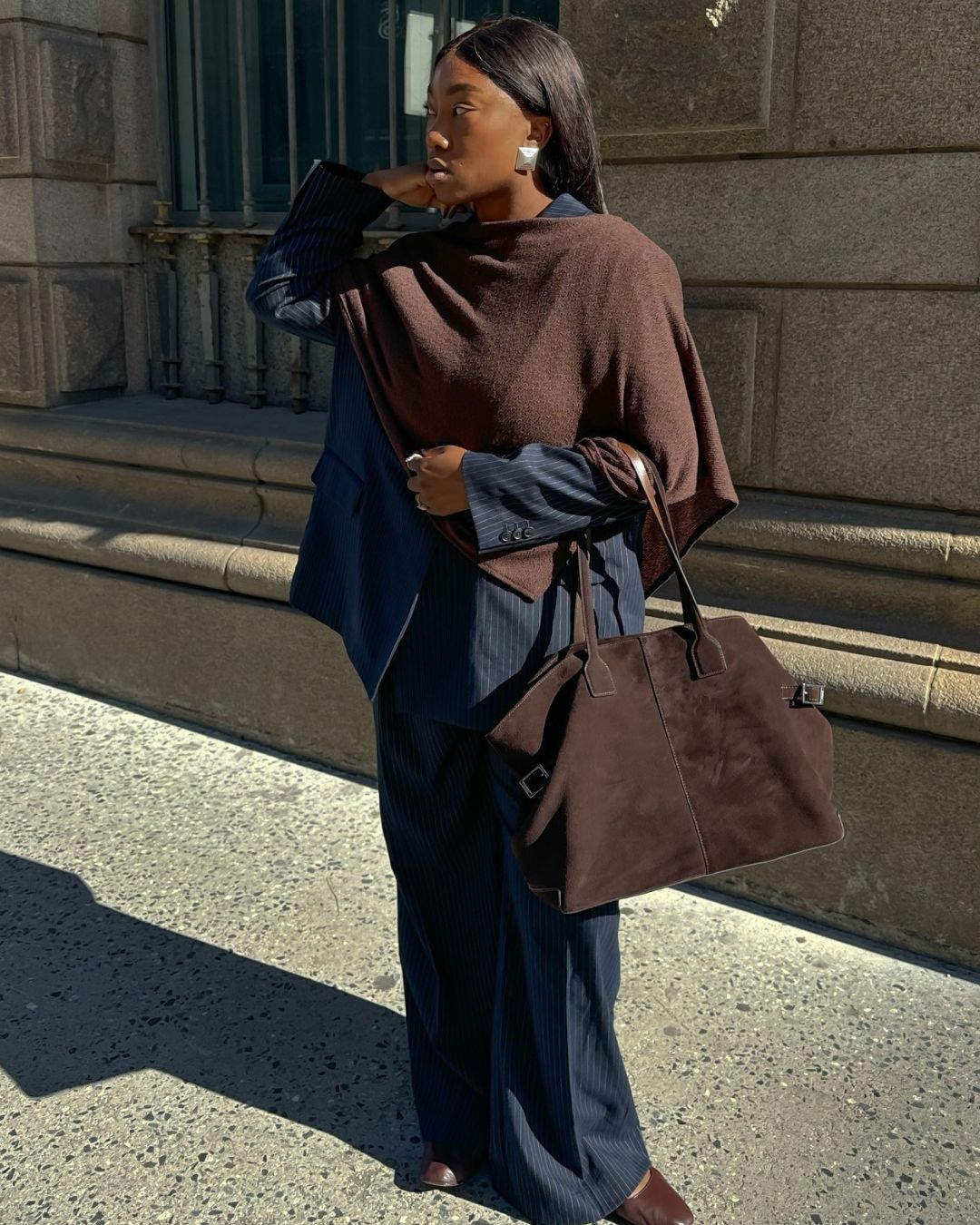 Influencer @nnennaechem wears a navy pinstripe suit with a brown scarf and brown suede tote.