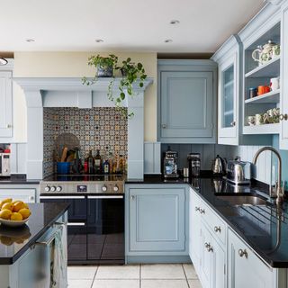 kitchen with pale blue cabinets and black worktops with kitchen appliances on display