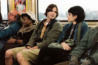 Oliver och Emily sitter bredvid varandra i en tågvagn och kollar på varandra.