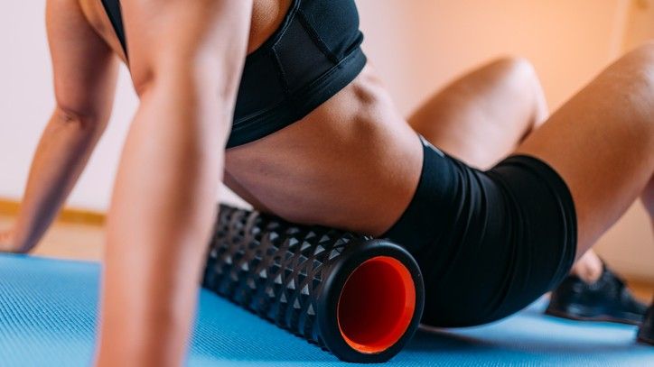 foam roller for back exercises: athletic women rolling her lower back with a foam roller