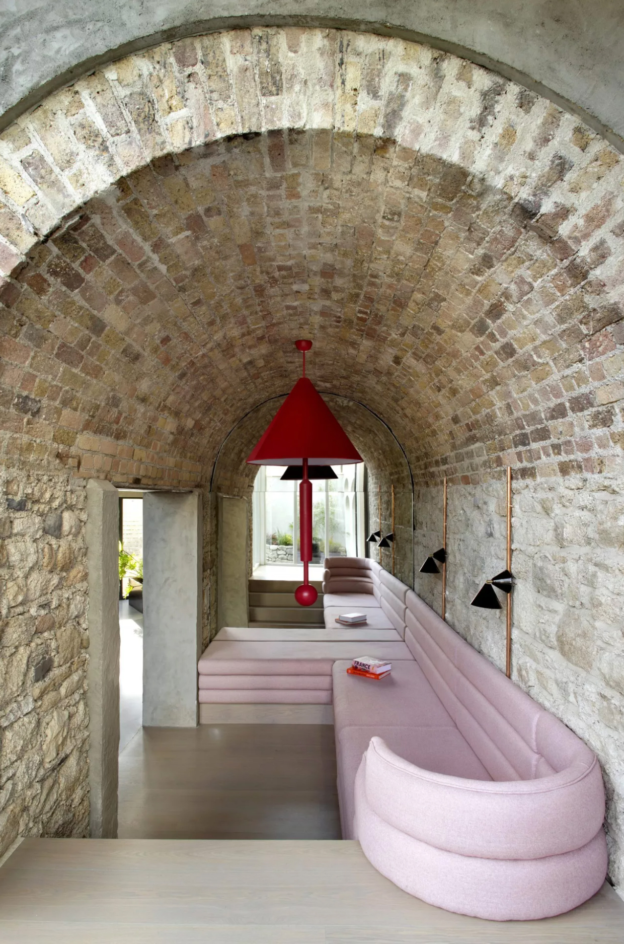 Pink curved sofa in arched living room with large mirror