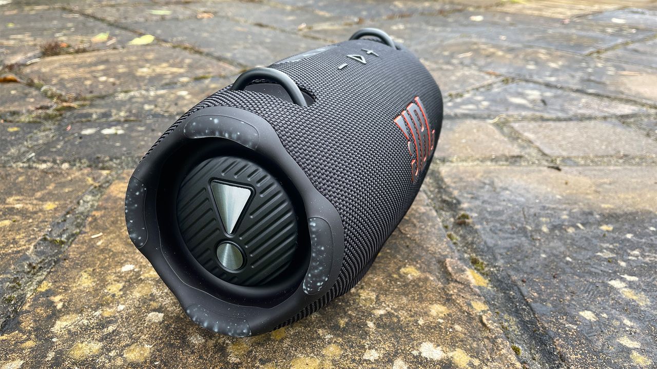 A black JBL Xtreme 4 wireless speaker on some paving slabs