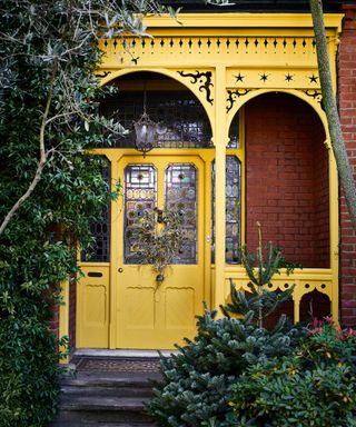 Yellow painted door and porch, wreath and pine trees