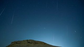meteors streak through a dark night sky