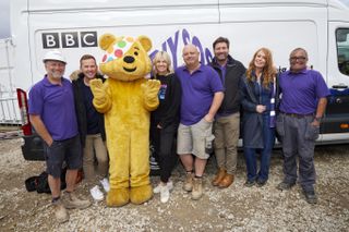 Nick Knowles and some of the DIY SOS team stand in front of a DIY SOS-branded van on the building site, joined by Pudsey Bear, Scott Mills and Zoe Ball