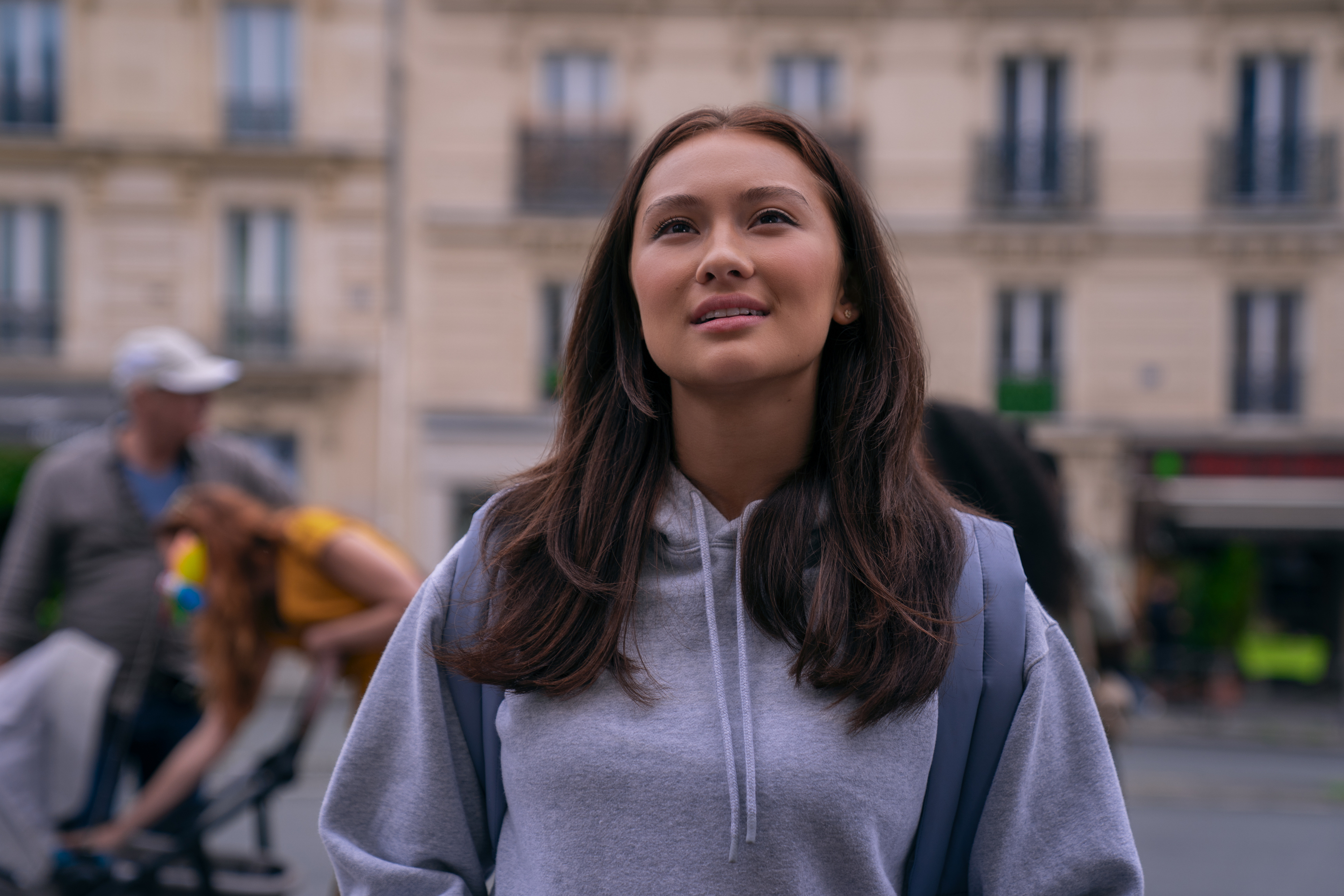 lola tung as belly wearing a sweatshirt walking through paris in a still from the summer i turned pretty season 3