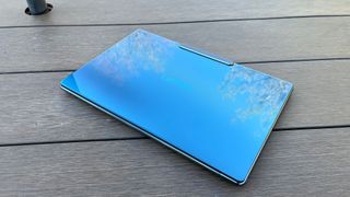 A Lenovo Yoga Slim 9i sitting on a picnic table outside