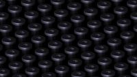 Close-up wallpaper showing dozens of dark metallic torque screws arranged in a repeating grid pattern against a black background, created for Microsoft's Surface Laptop Ultra.