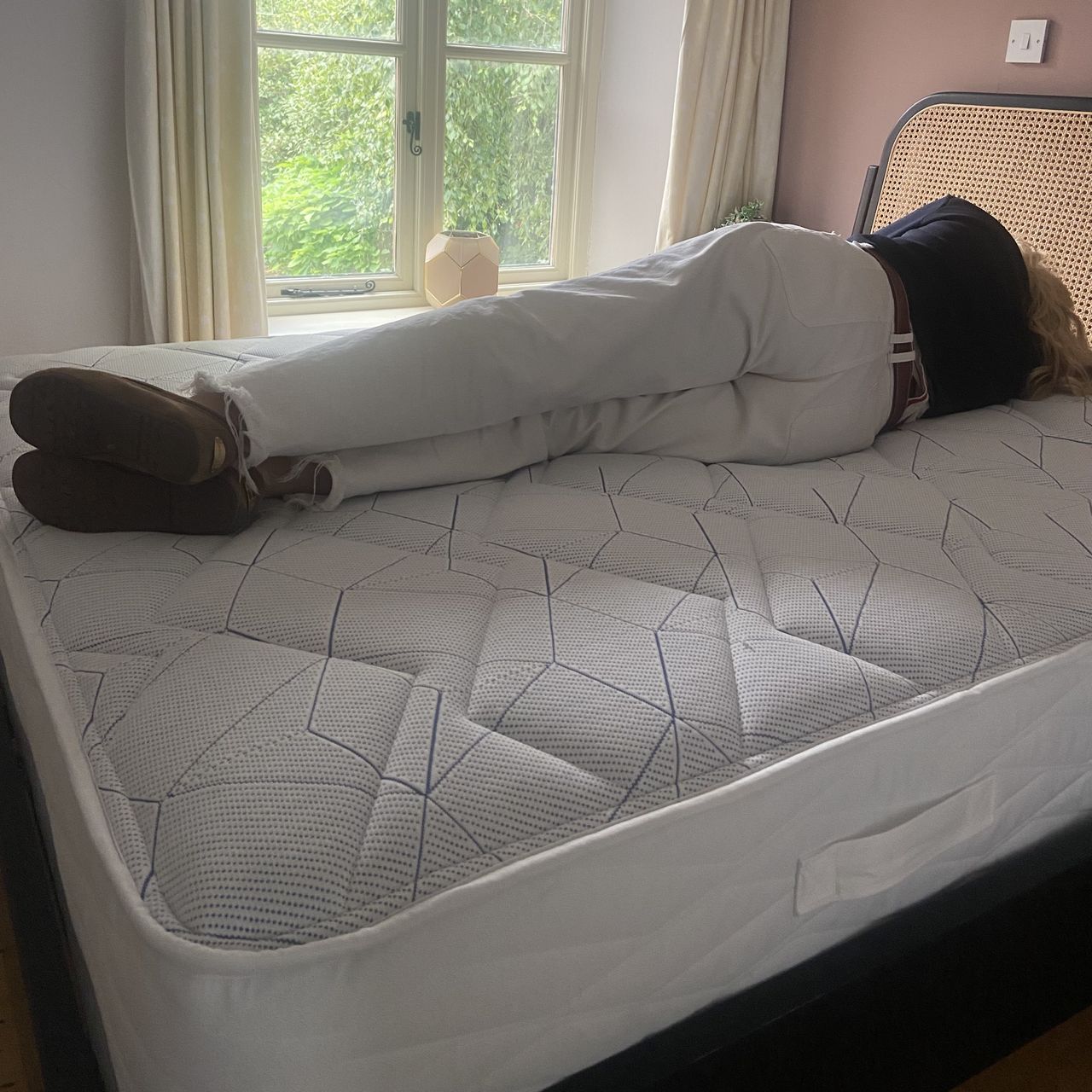 A woman in a black top and white trousers lying on her side on top of the Bensons for Beds Simply Support Pocket Sprung Mattress.