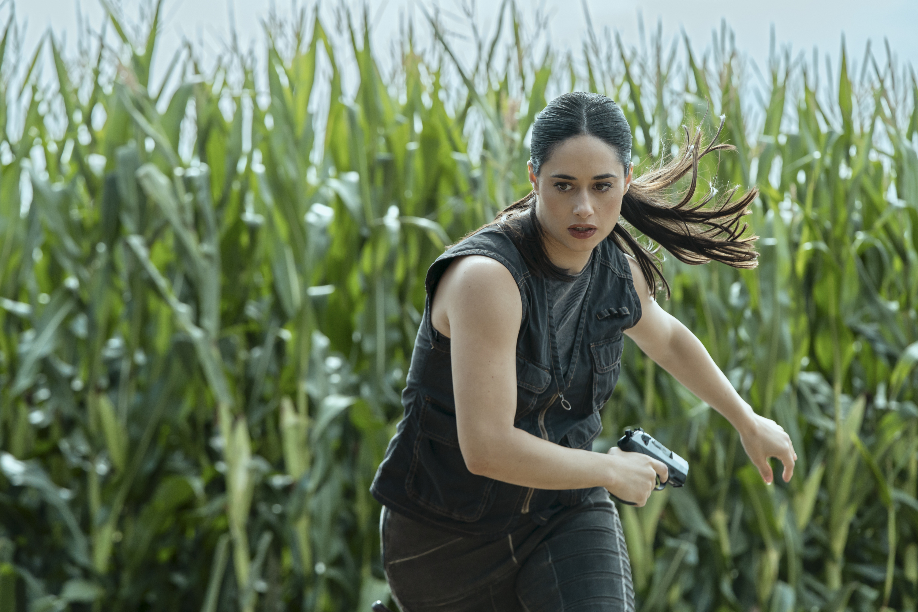 Rebecca Luz (Jeanine Mason) running through a field holding a gun in the finale of cross season 2