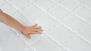 Woman hand testing orthopedic memory foam core mattress