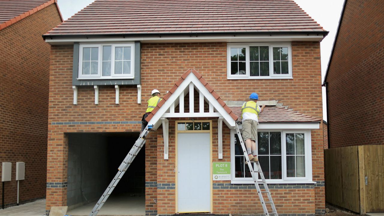 Construction workers build new houses on a housing development in Middlewich, England