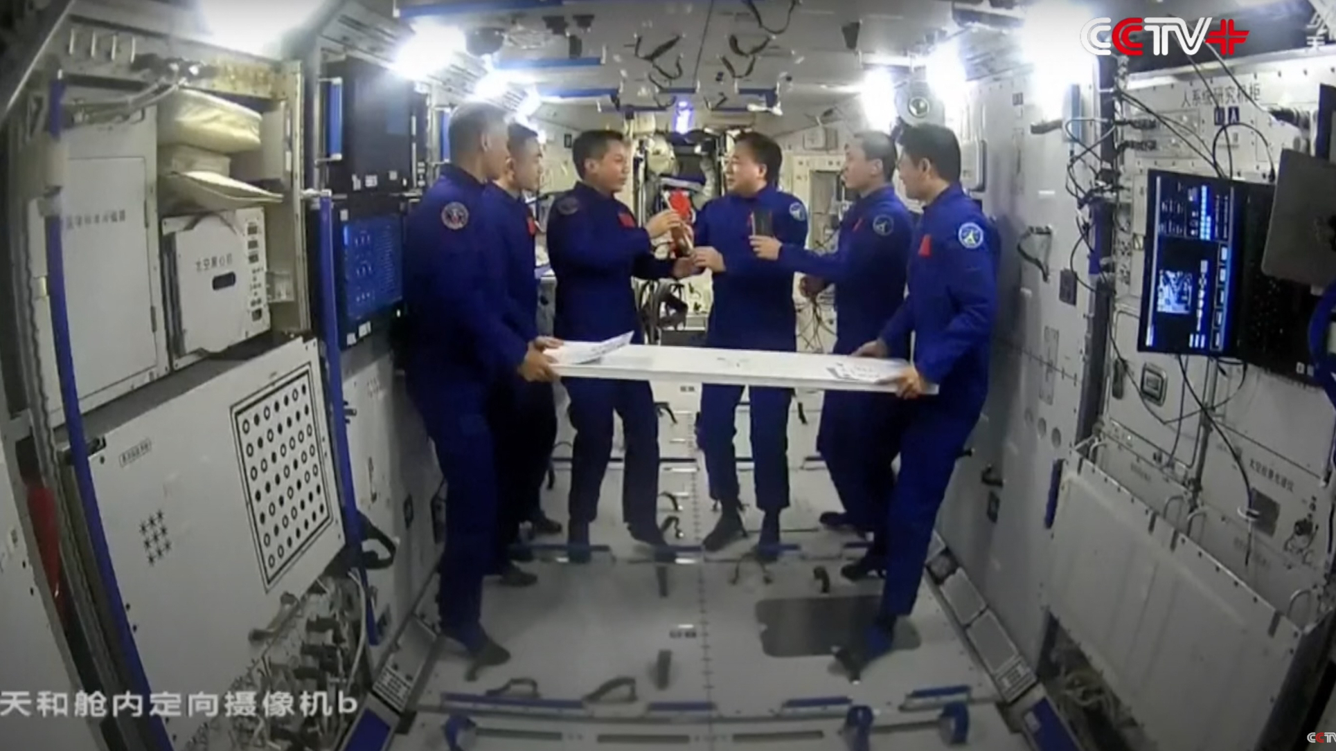 Breaking News six astronauts in blue flight suits circulation aboard a local residing with white partitions.