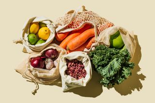 Cotton bags full of a variety of colourful vegetables.