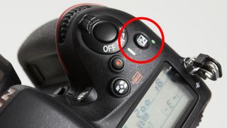 Close-up of Nikon D600 top plate, with red circle highlighting the exposure compensation button