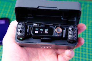 A photo of the DJI Mic 2 (TX/RX/Charging case) open in hand.