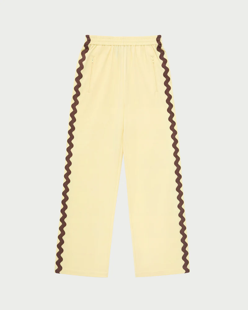 Butter yellow track pants with wavy brown line on the sides.
