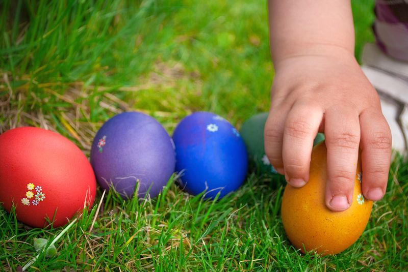 A child&#039;s hand reaches out to grab an Easter egg