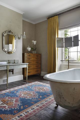 Clawfoot painted bath, stone wallpaper with light flower design. wooden cabinet