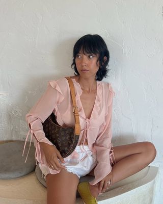 Woman wearing eyelet bloomer shorts and pink ruffle top.