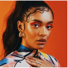 a model with stylized baby hairs posing in front of an orange background