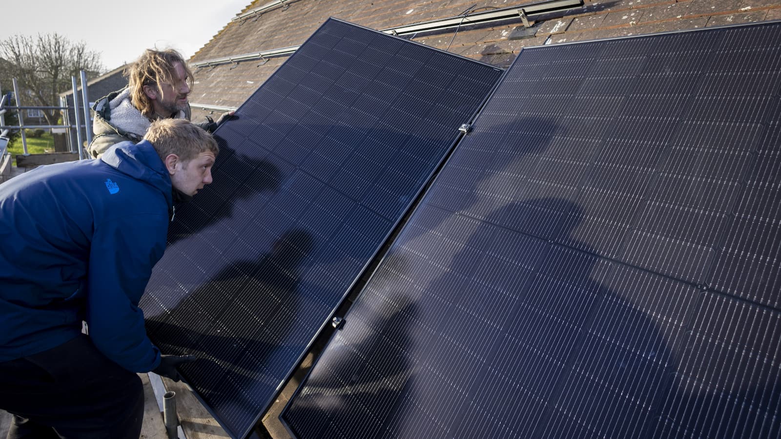Solar Panel Installers work on the roof top of a house to install solar panels