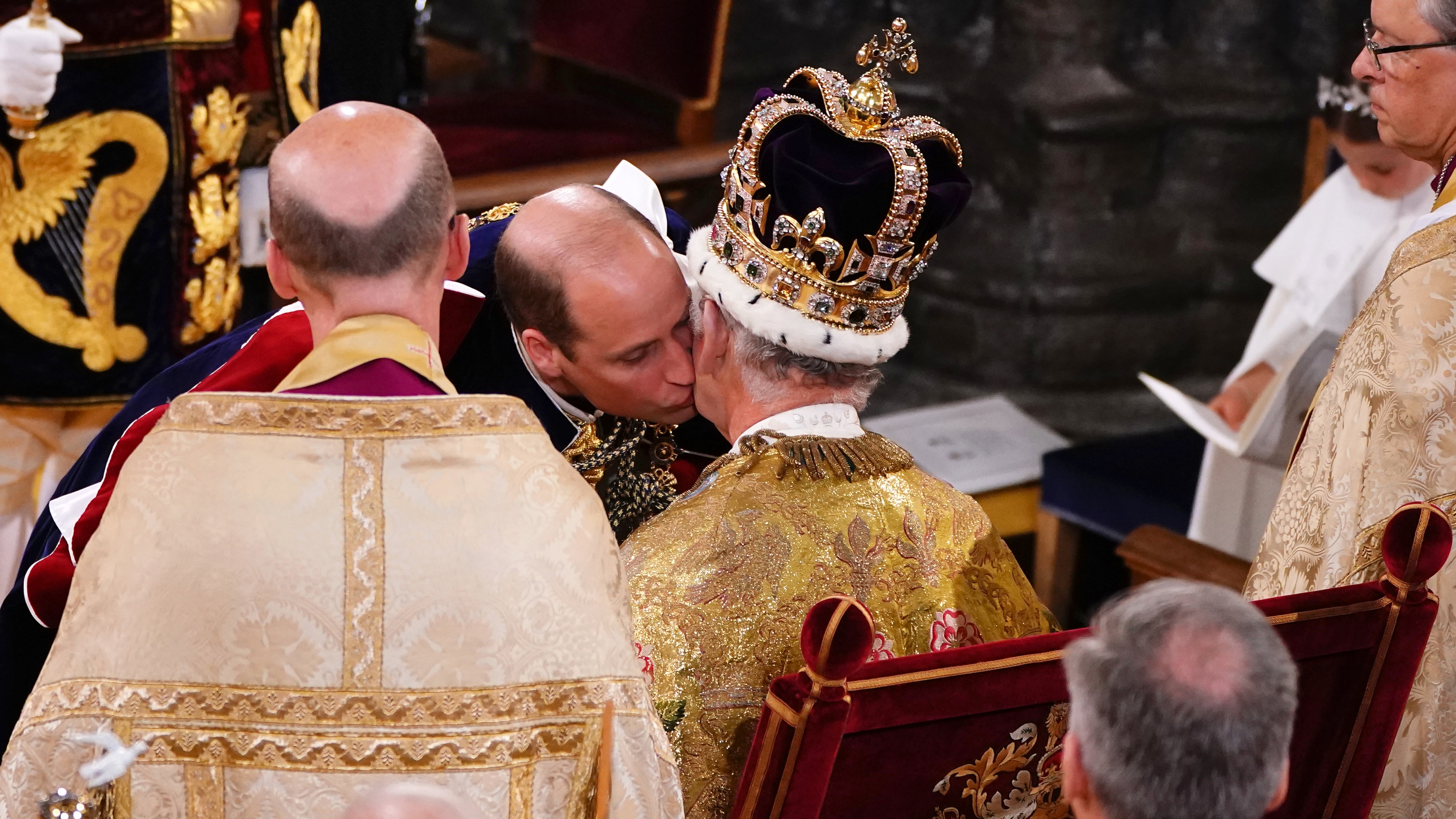 Prince William, Prince of Wales kisses his father, King Charles III, wearing St Edward's Crown, during the King's Coronation Ceremony