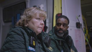 Jan and Jacob sitting at the back of an ambulance looking grave.