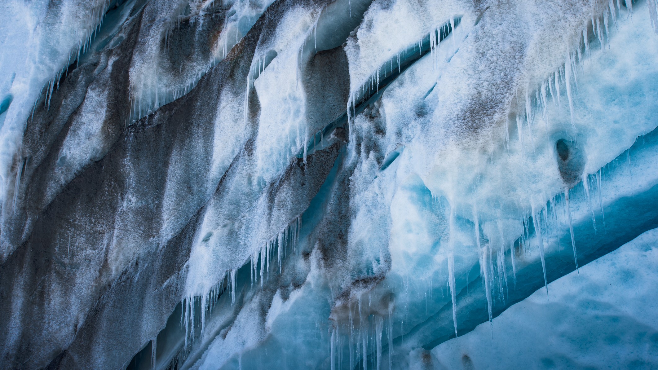 Layers of ice hanging off a glacier melt and drip water.
