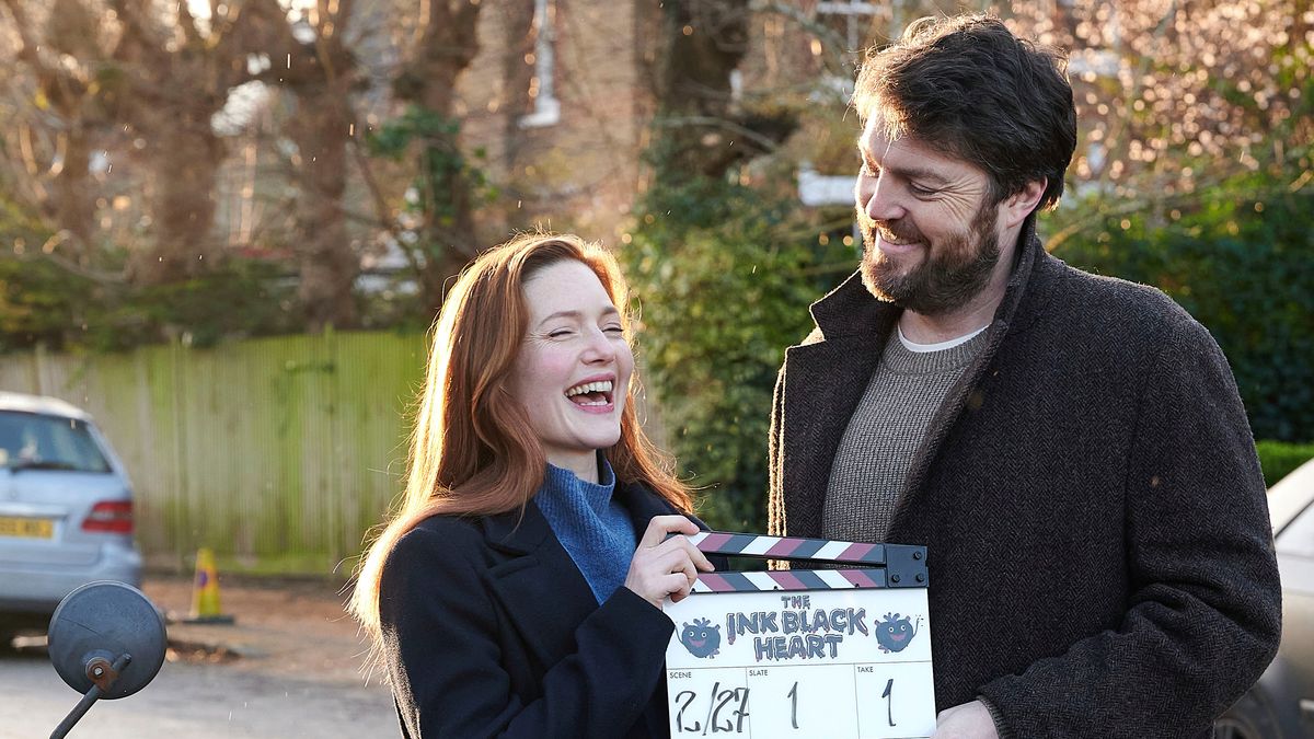 A Strike - The Ink Black Heart behind-the-scenes shot showing Robin Ellacott (Holliday Grainger) and Cormoran Strike (Tom Burke) on set.