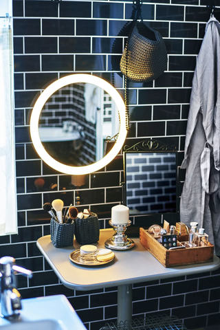 bathroom storage in a small bathroom with a round LED mirror and black metro tiles