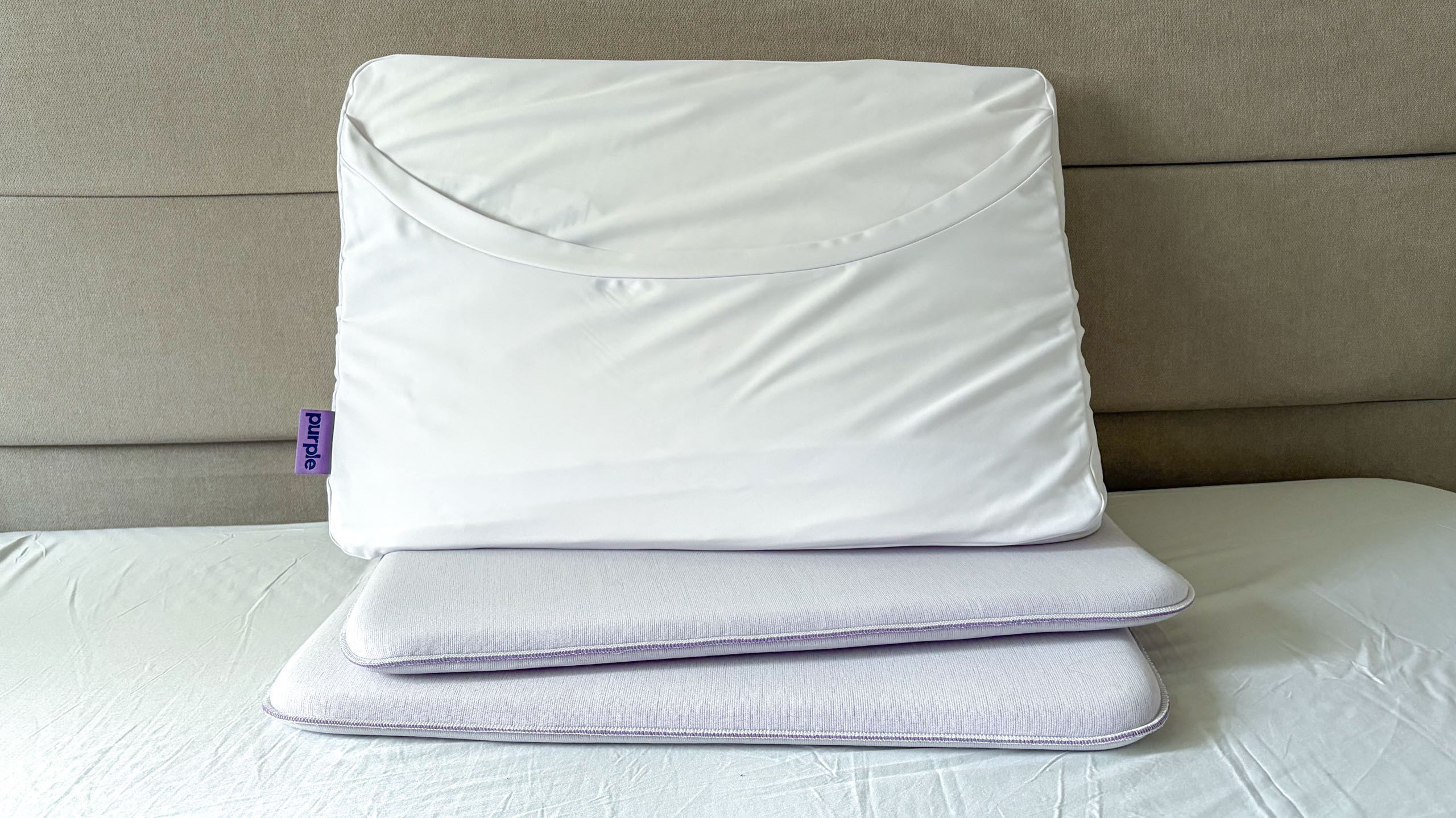 A close up of the Purple DreamLayer Pillow resting on its booster layers, on the bed in our reviewer's bedroom