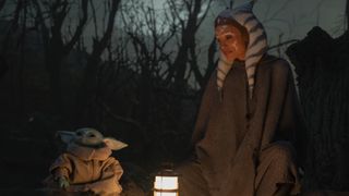 The Child and Ahsoka Tano (Rosario Dawson) sit together by lamplight in The Mandalorian Season 2.