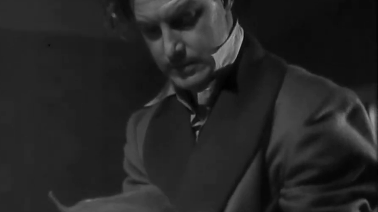 A man looking at the plans for the silent plane in The 39 Steps