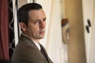 Death in Paradise's Neville (Ralf Little) looking into the distance with an expression of deep thought on his face