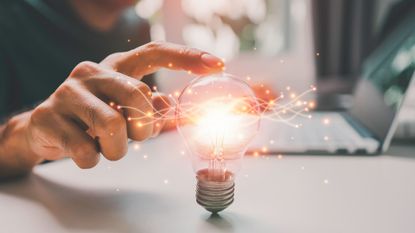 A businessperson touching a glowing lightbulb, to represent business values.