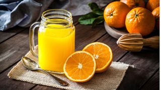 Glass of orange juice with oranges surrounding
