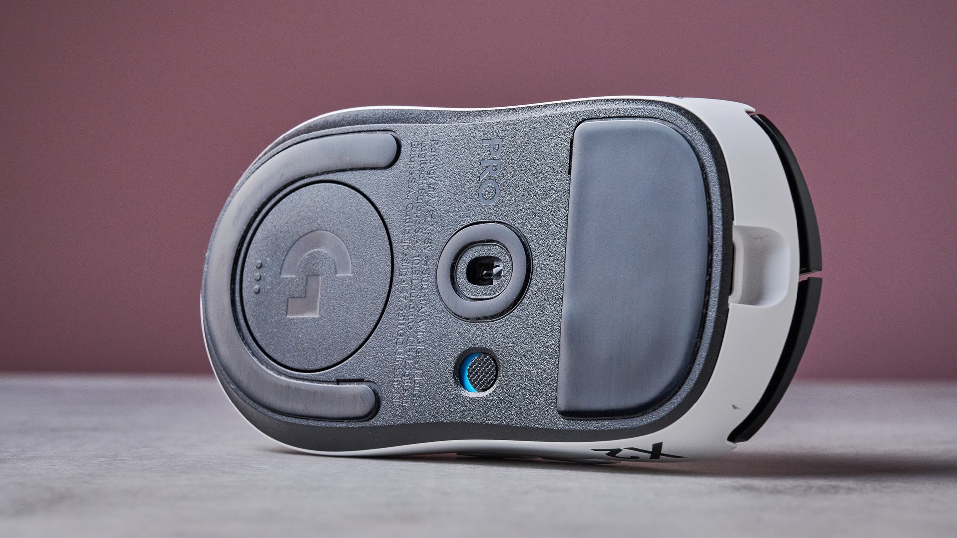 View of underneath of Logitech G Pro X2 Superstrike on white desk with pink wall in background