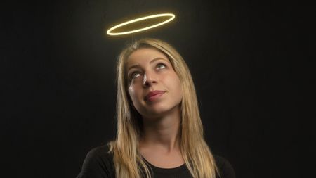 A woman looks up at a bright halo over her head. She looks somewhat amused by it being there.