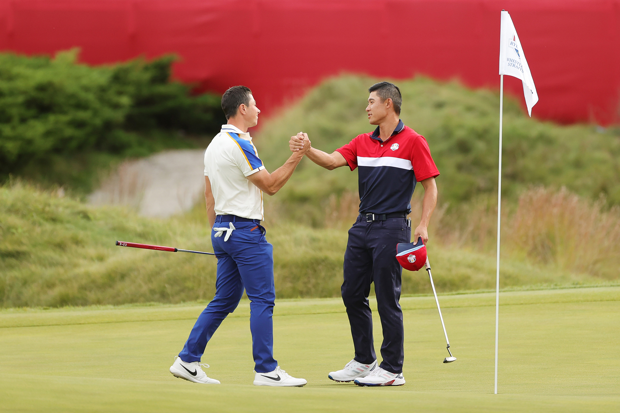 Viktor Hovland and Collin Morikawa shaking hands after their match ended all-square at the 2021 Ryder Cup, handing Team USA the victory