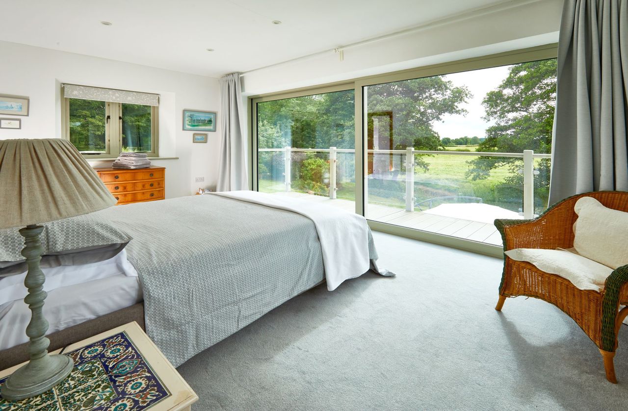 Bedroom with a terrace and floor to ceiling windows which shows the garden features