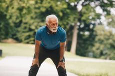 Senior man is resting after warming up exercises. He is going to continue working out, stretching and jogging, but for now he will take deep breath.