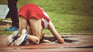 Young male athlete collapsing on the ground
