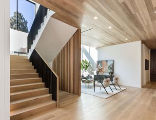 staircase with wide pale wood treads and wooden screen next to seating area